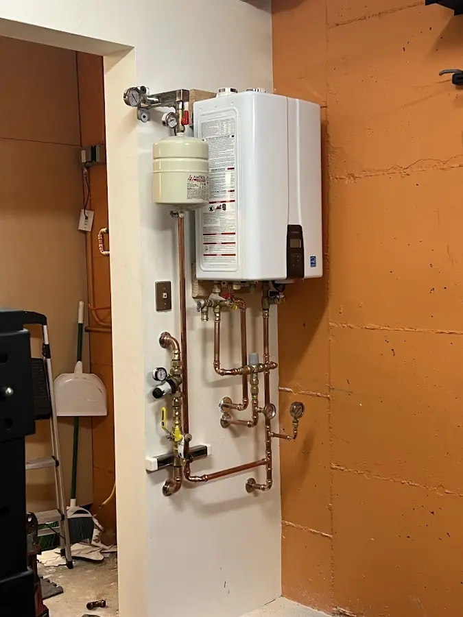 Plumbing technician inspecting water heater connections in Hobart
